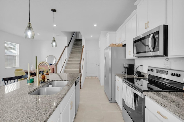 kitchen featuring appliances with stainless steel finishes, white cabinetry, sink, hanging light fixtures, and light stone counters