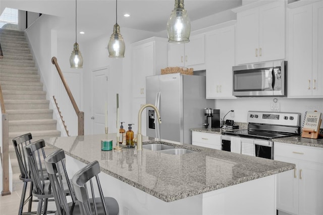 kitchen with decorative light fixtures, sink, an island with sink, and stainless steel appliances