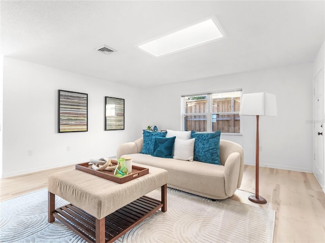 living area featuring visible vents, light wood-style flooring, and baseboards