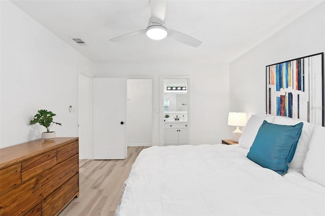 bedroom featuring ensuite bathroom, a sink, a ceiling fan, visible vents, and light wood-style floors