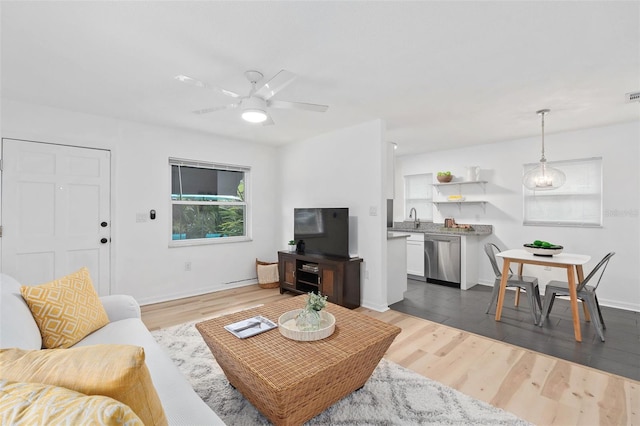 living area featuring baseboards, visible vents, a ceiling fan, and wood finished floors