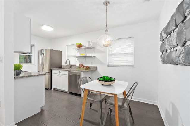 kitchen with stone countertops, stainless steel appliances, a sink, white cabinetry, and open shelves