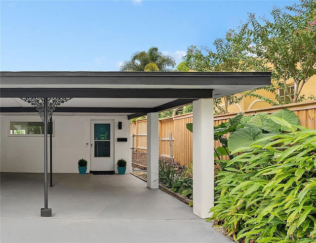 view of parking with a carport and fence