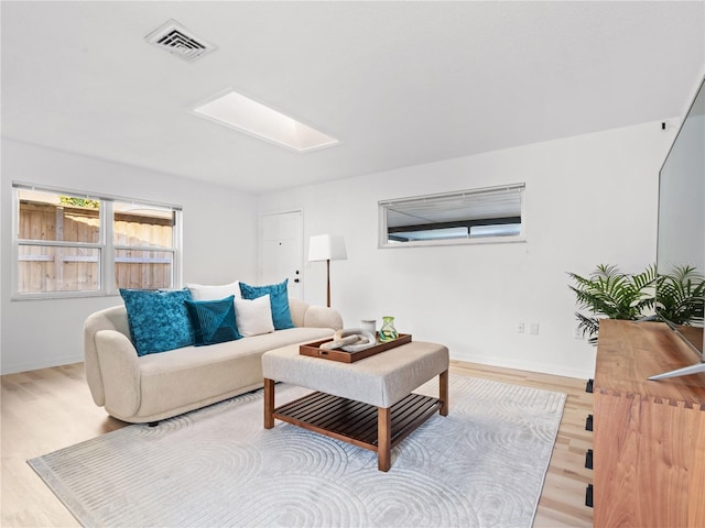 living room with baseboards, visible vents, and wood finished floors