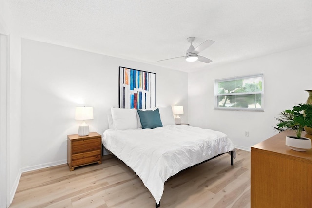 bedroom with light wood-style floors, ceiling fan, and baseboards