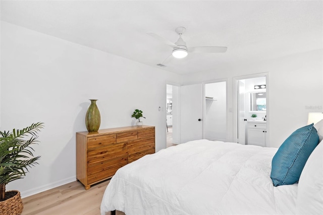 bedroom with light wood finished floors, visible vents, ensuite bathroom, a ceiling fan, and baseboards