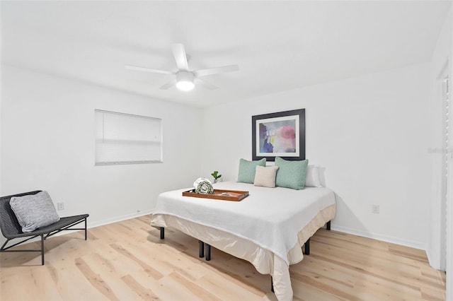 bedroom with a ceiling fan, baseboards, and light wood finished floors