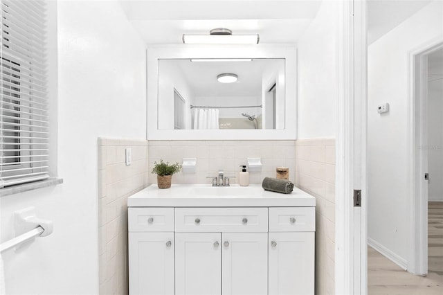 full bath with a shower with curtain, wood finished floors, tile walls, and vanity