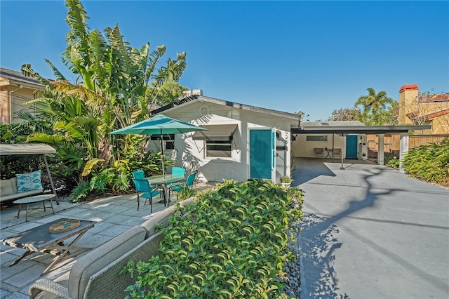 exterior space featuring a carport, stucco siding, concrete driveway, and a patio