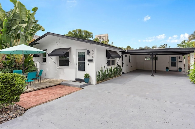 view of front of house featuring an attached carport, driveway, and stucco siding