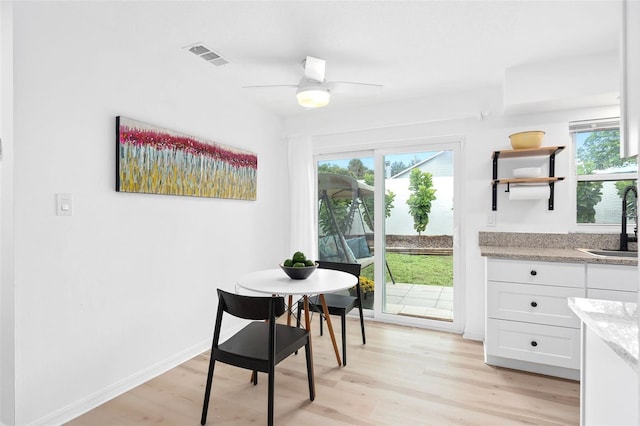 dining room with a healthy amount of sunlight, sink, and light wood-type flooring