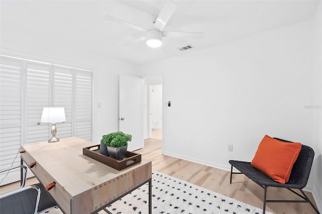 home office with light hardwood / wood-style flooring and ceiling fan