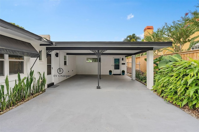 view of parking / parking lot with a carport, fence, and driveway