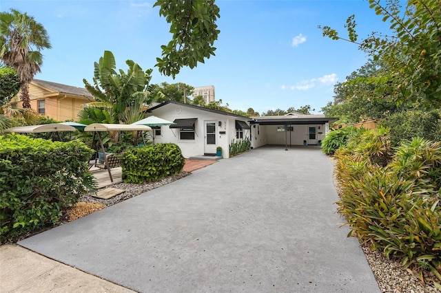 view of front of home featuring a carport, driveway, and stucco siding