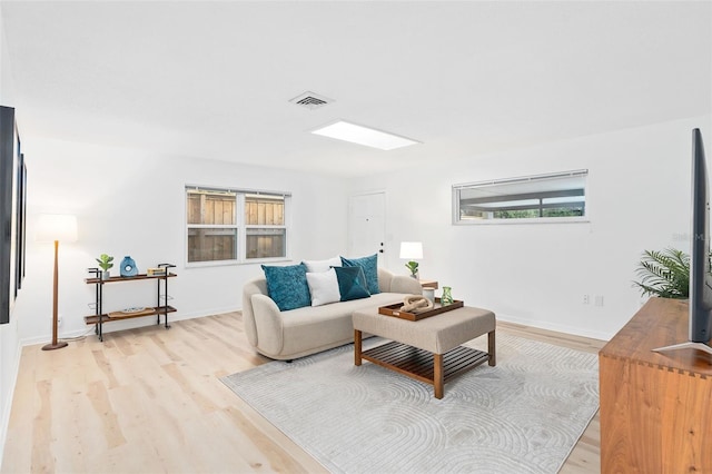 living room featuring light wood-type flooring, baseboards, and visible vents