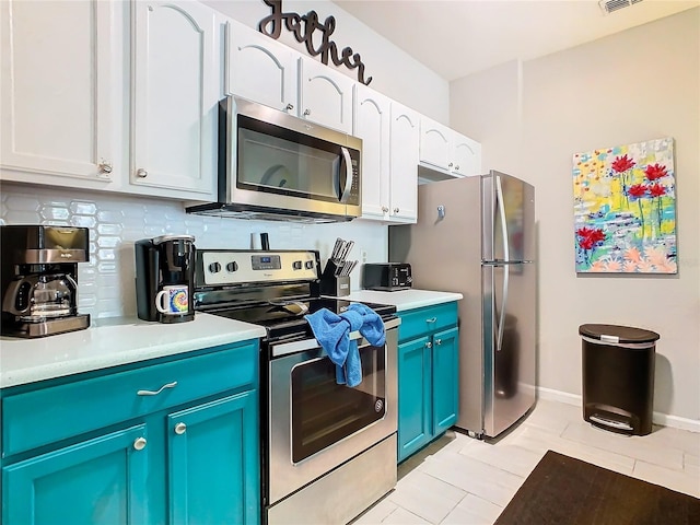 kitchen featuring white cabinets, light tile patterned flooring, blue cabinetry, and stainless steel appliances