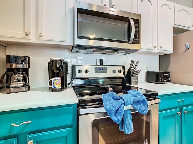 kitchen with white cabinets, backsplash, appliances with stainless steel finishes, and blue cabinetry