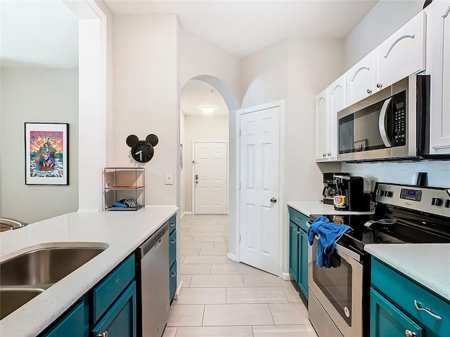 kitchen featuring appliances with stainless steel finishes, white cabinetry, blue cabinetry, sink, and light tile patterned floors