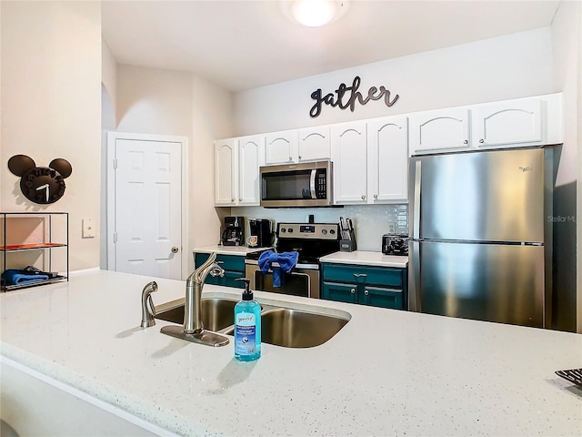 kitchen with light stone countertops, sink, white cabinets, and stainless steel appliances