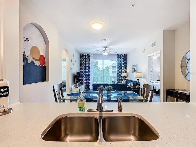 kitchen with ceiling fan, light stone countertops, and sink