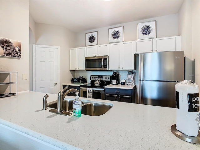 kitchen with light stone countertops, sink, white cabinetry, and stainless steel appliances