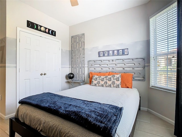 tiled bedroom featuring ceiling fan and a closet