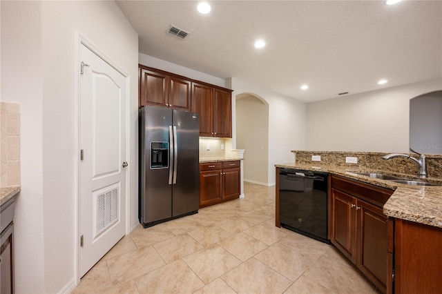 kitchen with sink, light tile patterned floors, stainless steel fridge, black dishwasher, and light stone countertops