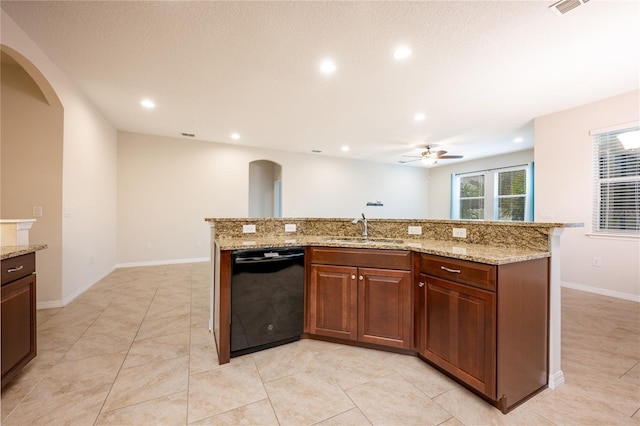 kitchen featuring sink, dishwasher, ceiling fan, light stone countertops, and an island with sink