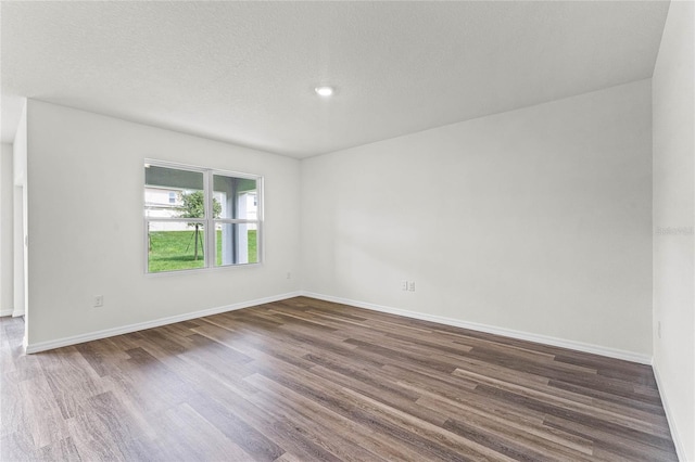 spare room with dark hardwood / wood-style floors and a textured ceiling