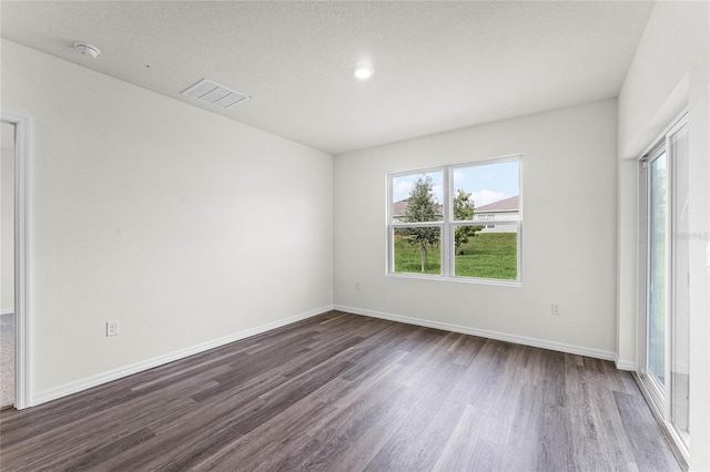 unfurnished room with dark wood-type flooring, a wealth of natural light, and a textured ceiling