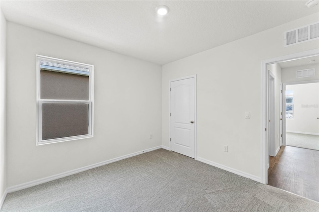 carpeted empty room featuring a textured ceiling