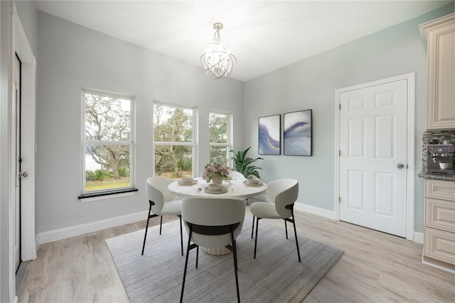 dining space with light wood-type flooring and a notable chandelier