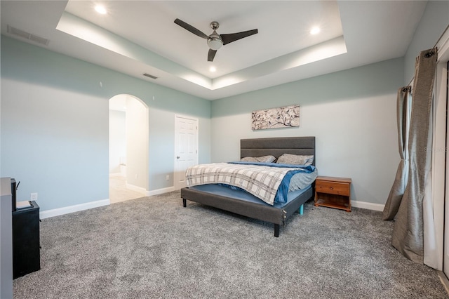 bedroom featuring ceiling fan, a raised ceiling, and carpet flooring