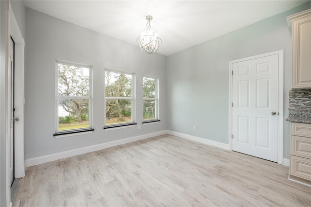 unfurnished dining area featuring light wood-type flooring and an inviting chandelier