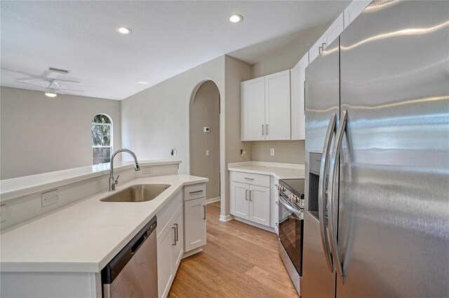 kitchen featuring sink, white cabinets, ceiling fan, stainless steel appliances, and light wood-type flooring