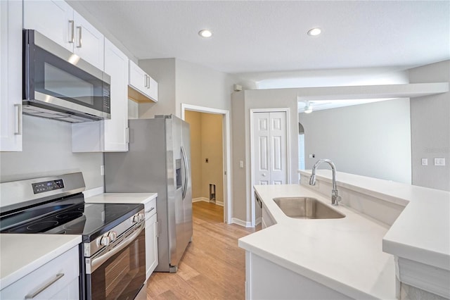 kitchen featuring sink, light hardwood / wood-style flooring, appliances with stainless steel finishes, white cabinetry, and a textured ceiling