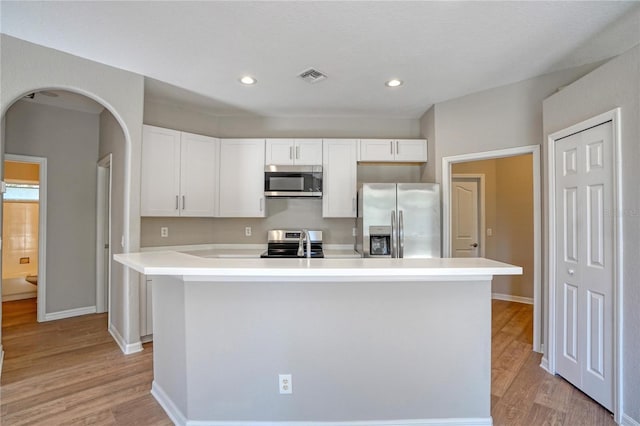 kitchen featuring appliances with stainless steel finishes, a center island with sink, white cabinets, and light hardwood / wood-style floors