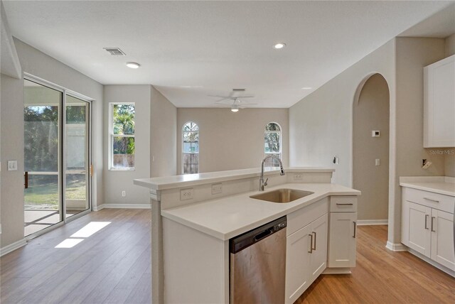 kitchen featuring sink, white cabinetry, light wood-type flooring, stainless steel dishwasher, and a kitchen island with sink