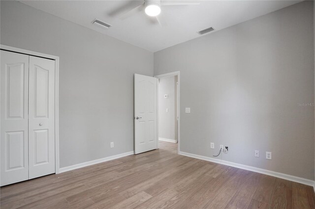 unfurnished bedroom featuring light hardwood / wood-style floors, a closet, and ceiling fan