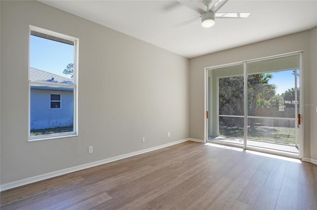 spare room with wood-type flooring, a healthy amount of sunlight, and ceiling fan