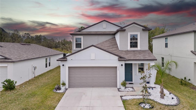 traditional home with concrete driveway, roof with shingles, stucco siding, a garage, and a yard