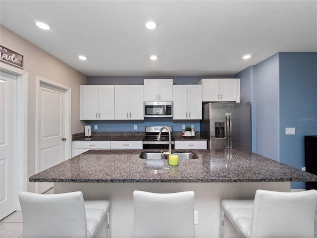 kitchen featuring a kitchen island with sink, appliances with stainless steel finishes, sink, and a breakfast bar area