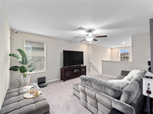 living room featuring light carpet, a healthy amount of sunlight, ceiling fan, and a textured ceiling