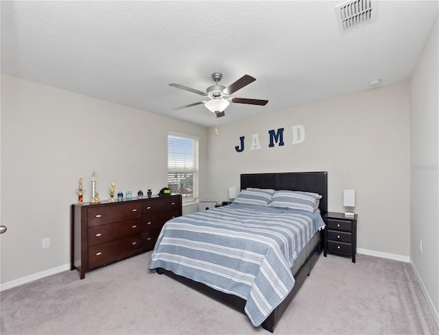 bedroom featuring ceiling fan, light carpet, and a textured ceiling