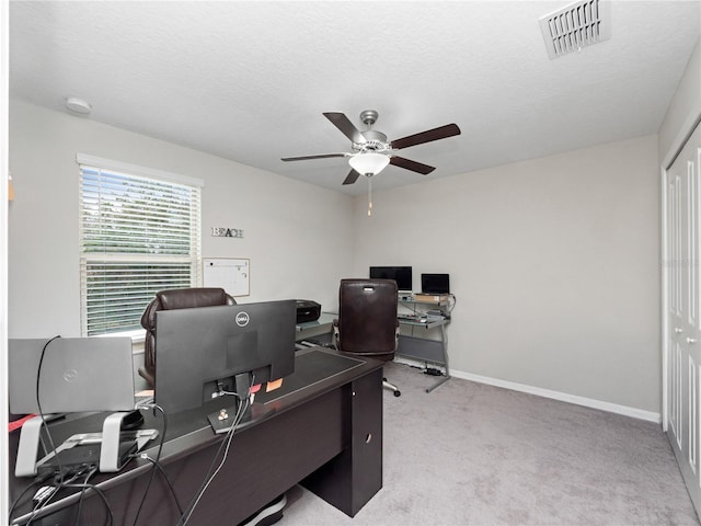 office space featuring light carpet, ceiling fan, and a textured ceiling