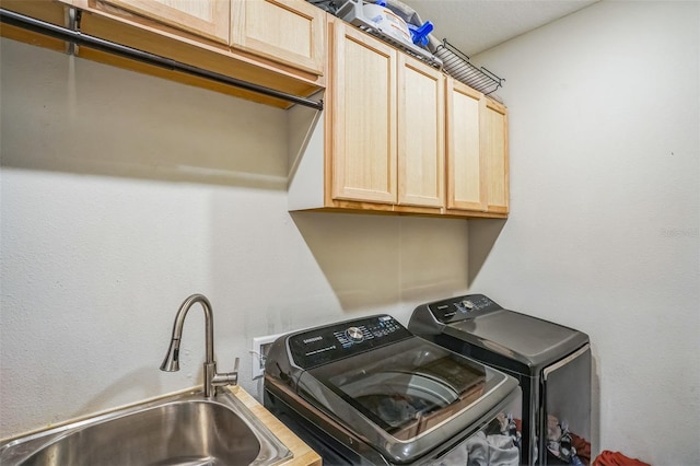 laundry area with cabinets, sink, and washer and clothes dryer