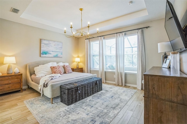 bedroom featuring a notable chandelier and a tray ceiling