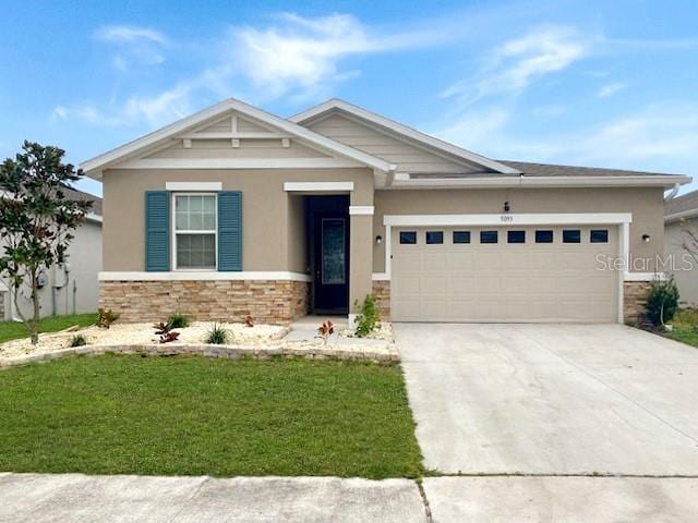 craftsman house with stucco siding, an attached garage, a front yard, stone siding, and driveway