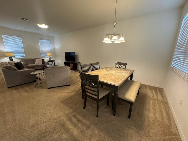 carpeted dining area featuring a chandelier