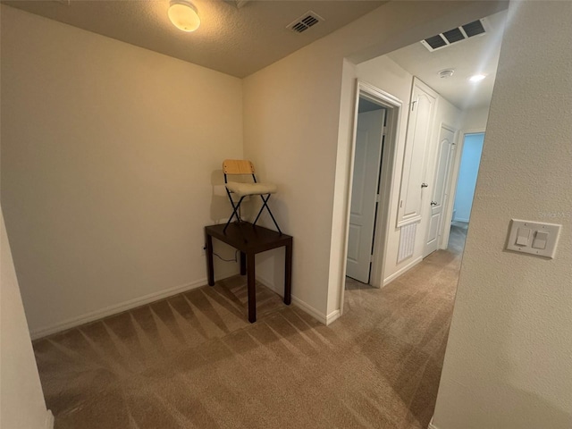 hall with carpet floors and a textured ceiling